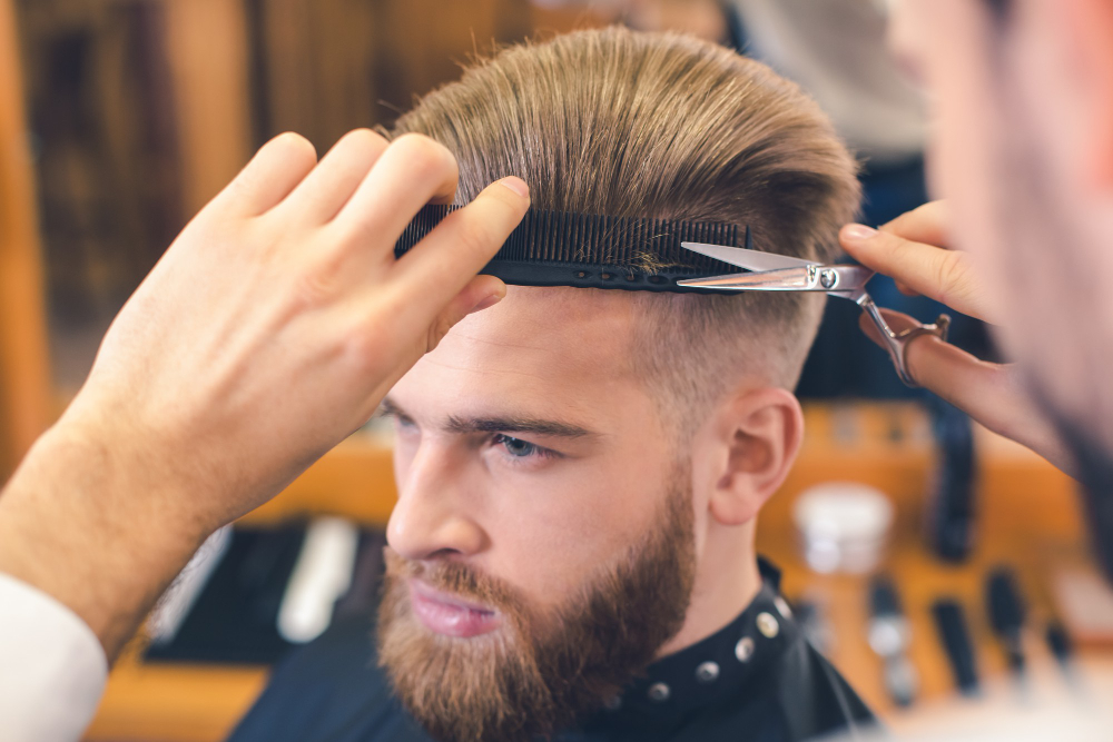 young-man-sitting-barbershop-while-barber-cutting-hair[4444]
